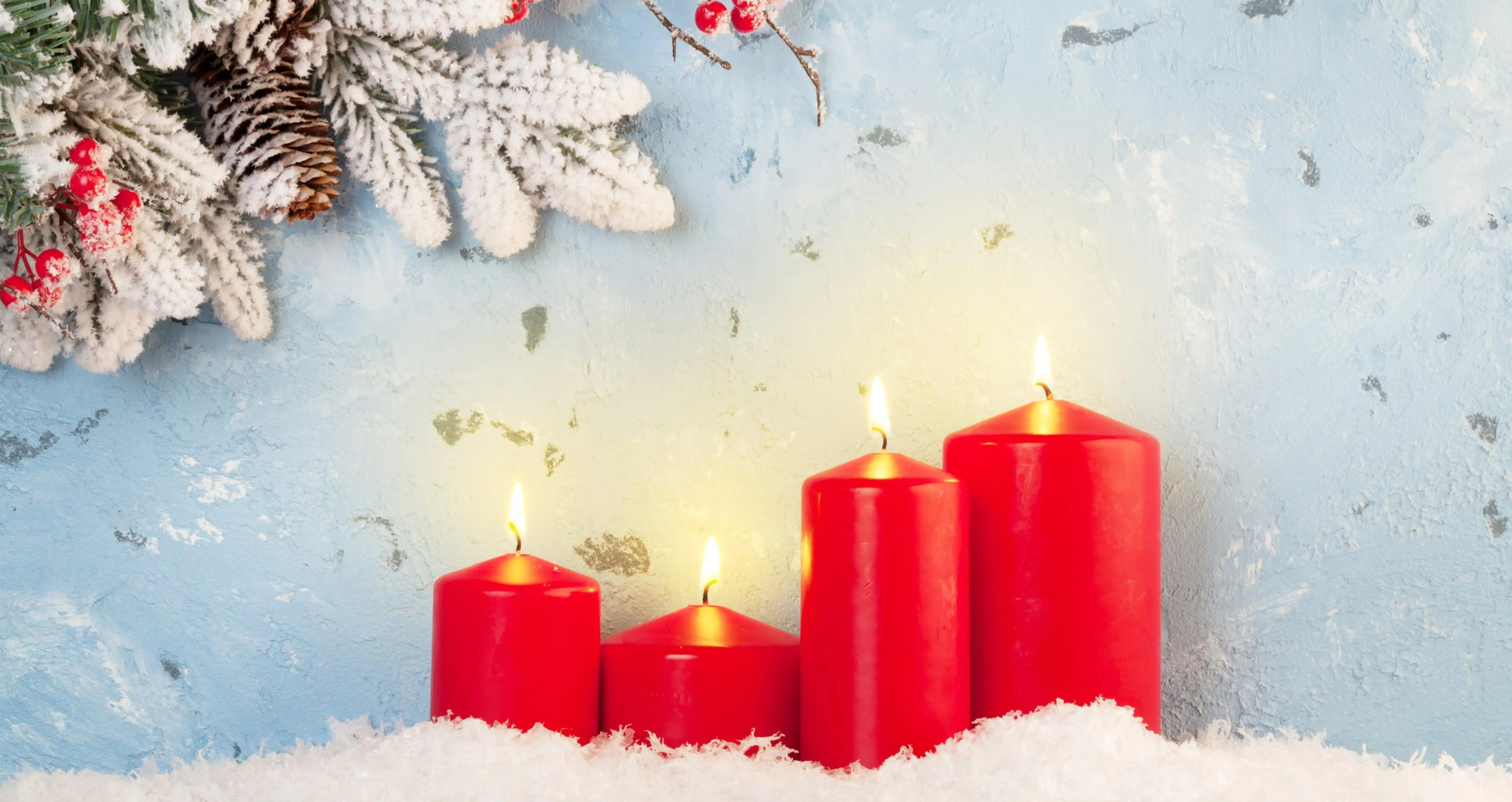 4 rote Adventskerzen mit Tannenzweig und Schnee